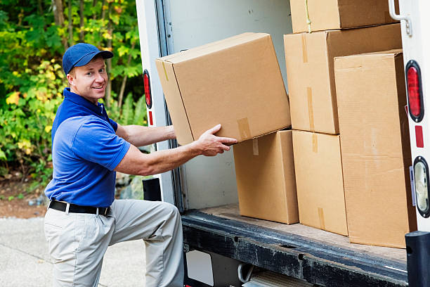 photo of a delivery man lifting cardboard boxes from the back of his truck.